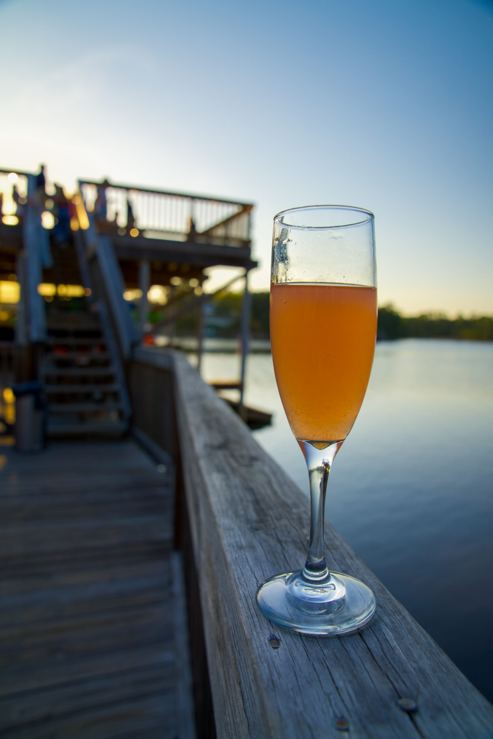 Sparkling rosé served in a champagne flute overlooking the waterfront dock at sunset at Old Florida Fish House.