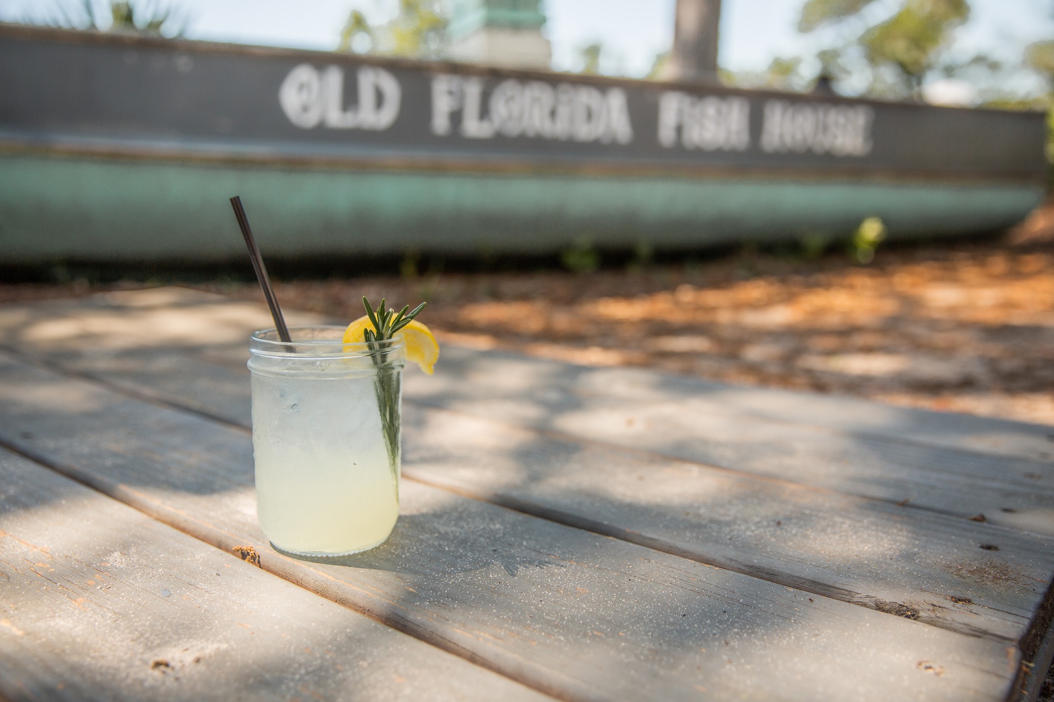 Signature handcrafted cocktail with rosemary and lemon garnish served outside Old Florida Fish House.